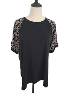 A black short-sleeve top with beige floral lace sleeves, displayed on a dress form mannequin against a white background.