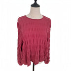 A dusty rose pink long-sleeve blouse with a textured crinkled fabric, displayed on a dress form