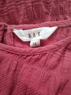 Close-up of a dusty rose pink textured knit top with a white neck label reading 'MAX' and size '14'.