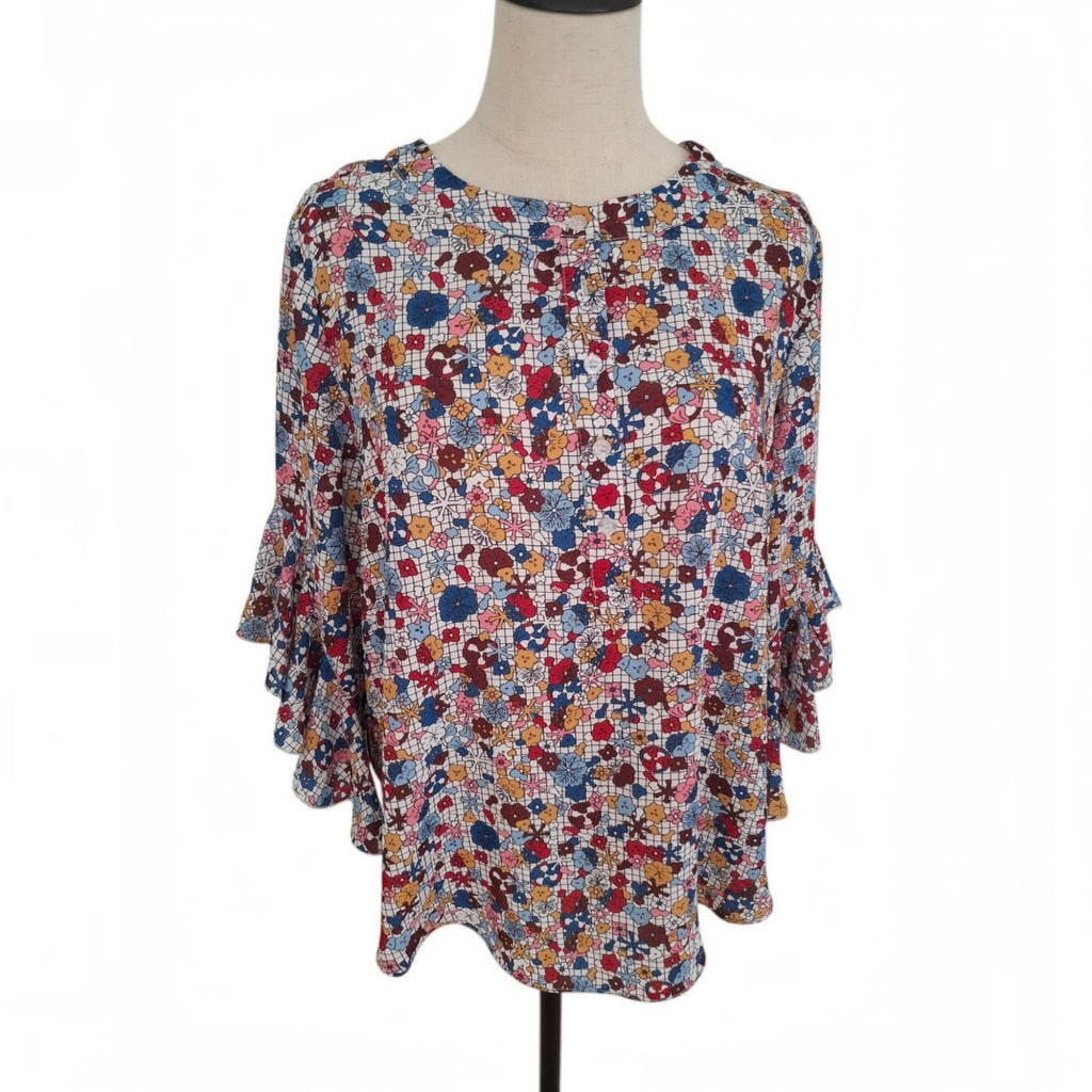 A women's short-sleeve blouse with a dense multicolor floral print, displayed on a mannequin torso against a plain white background.