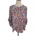 A women's short-sleeve blouse with a dense multicolor floral print, displayed on a mannequin torso against a plain white background.