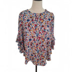 A women's short-sleeve blouse with a dense multicolor floral print, displayed on a mannequin torso against a plain white background.