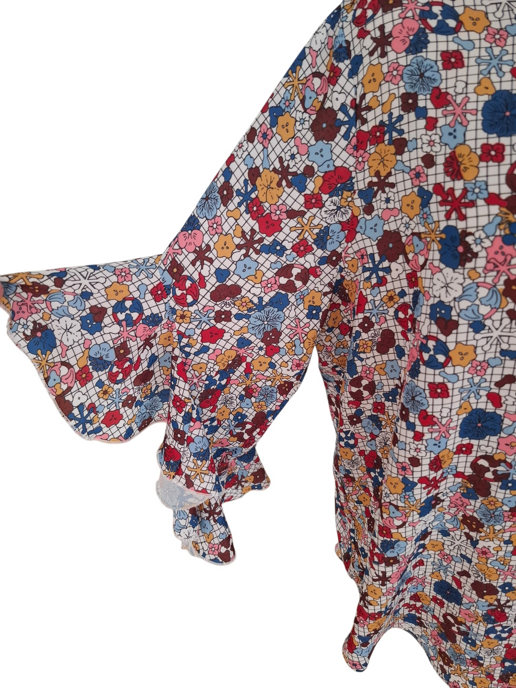 A close-up of a long-sleeve blouse with a ruffled cuff and a dense multicolor floral print on a white base, shown against a plain white background.