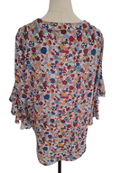 A women's long-sleeve blouse with a colorful patchwork floral print, displayed on a dress form mannequin against a white background.