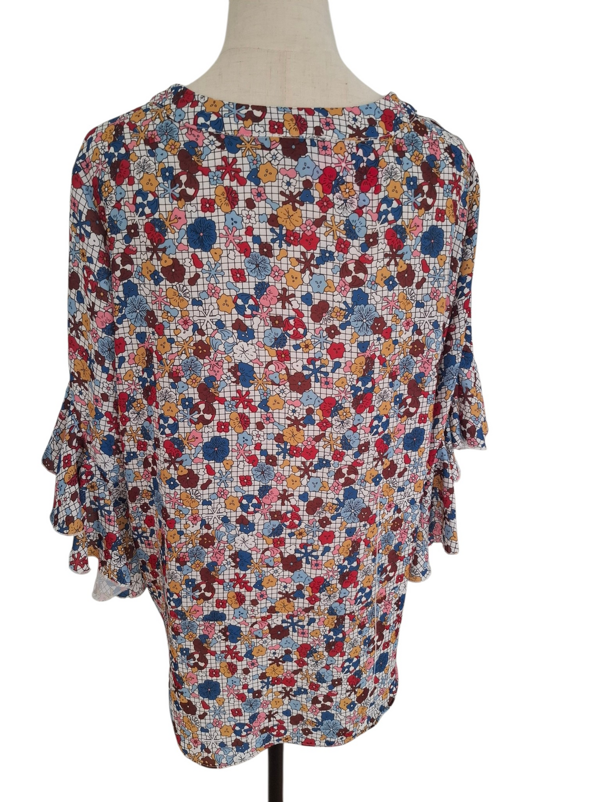 A women's long-sleeve blouse with a colorful patchwork floral print, displayed on a dress form mannequin against a white background.