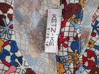 Close-up of a colorful floral and grid-patterned garment fabric with a white sewn-in size tag reading KETZ-KE SIZE 12.