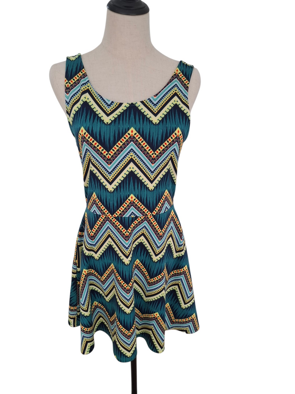 A sleeveless scoop-neck dress displayed on a mannequin torso against a plain white background. The dress features a vibrant chevron pattern with teal, navy, yellow, and orange stripes.