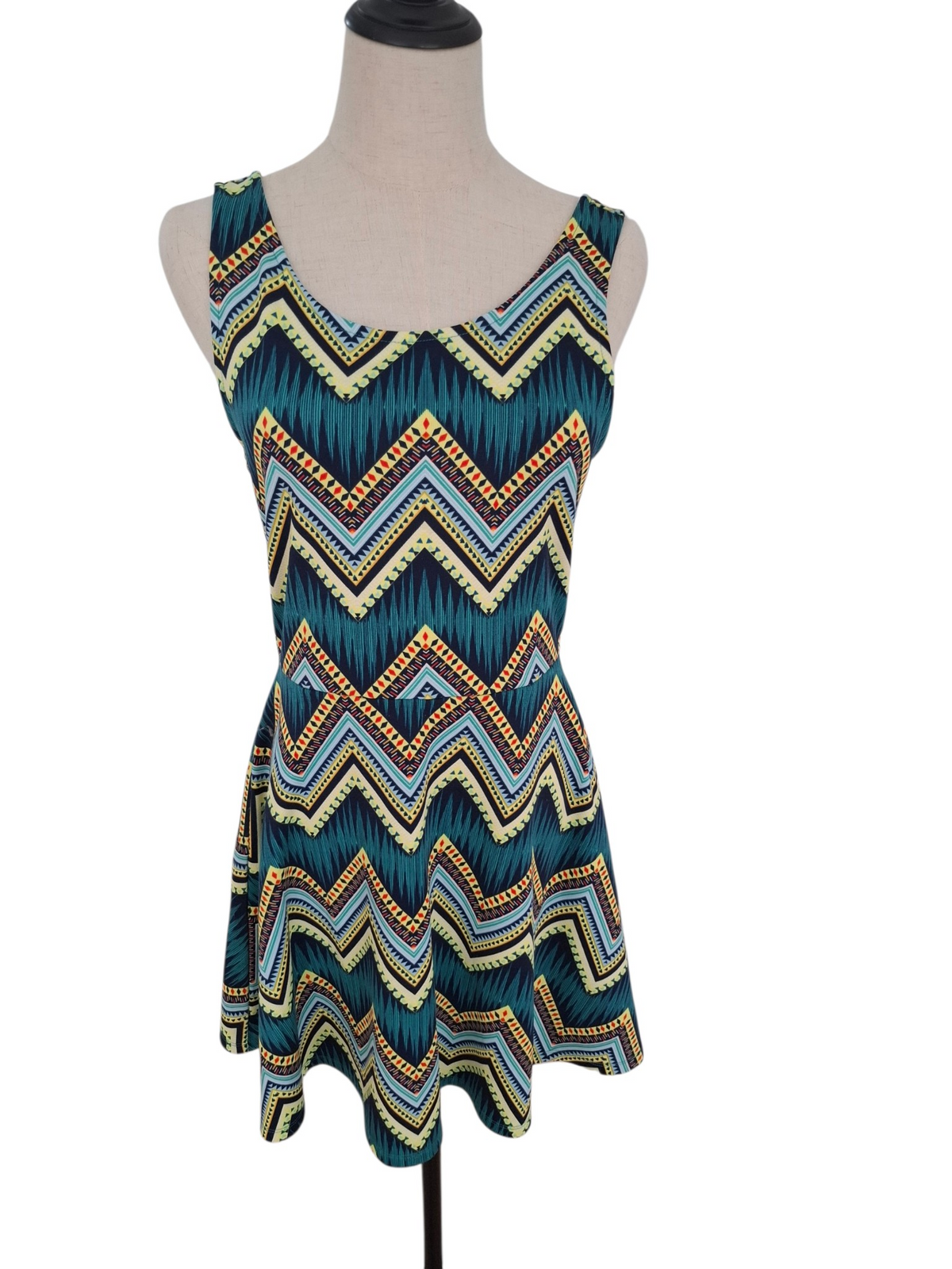A sleeveless scoop-neck dress displayed on a mannequin torso against a plain white background. The dress features a vibrant chevron pattern with teal, navy, yellow, and orange stripes.