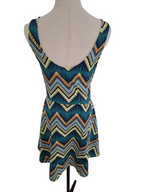 A sleeveless peplum top with a deep scoop back, featuring a colorful chevron pattern in teal, light blue, yellow, and orange, displayed on a beige dress form against a white background.