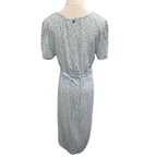 A light blue short-sleeve midi dress with a small multicolor floral print, shown from the back on a mannequin against a white background.