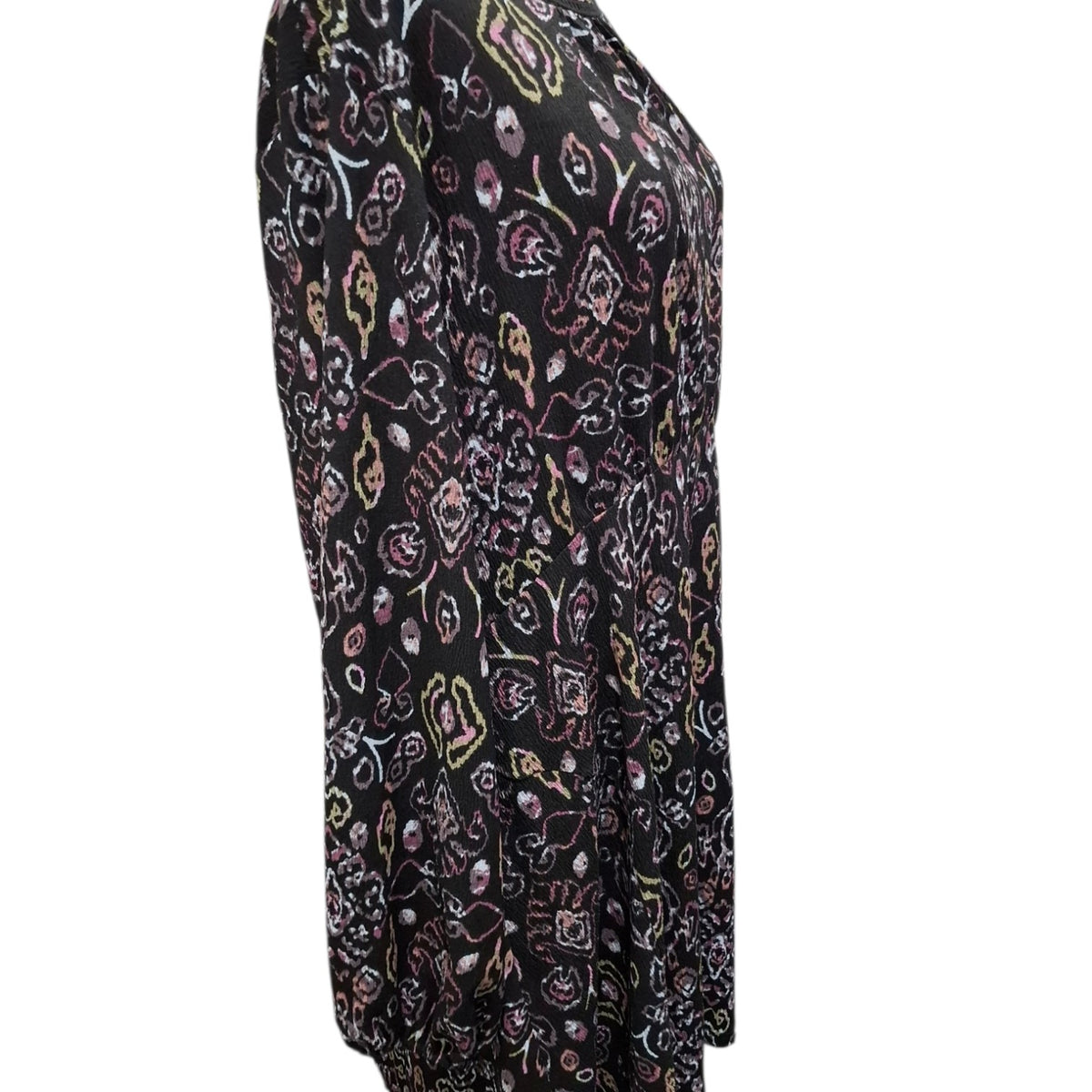 A black long-sleeve top with an all-over abstract floral and paisley print in pink, purple, white, and yellow, shown on a plain white background.