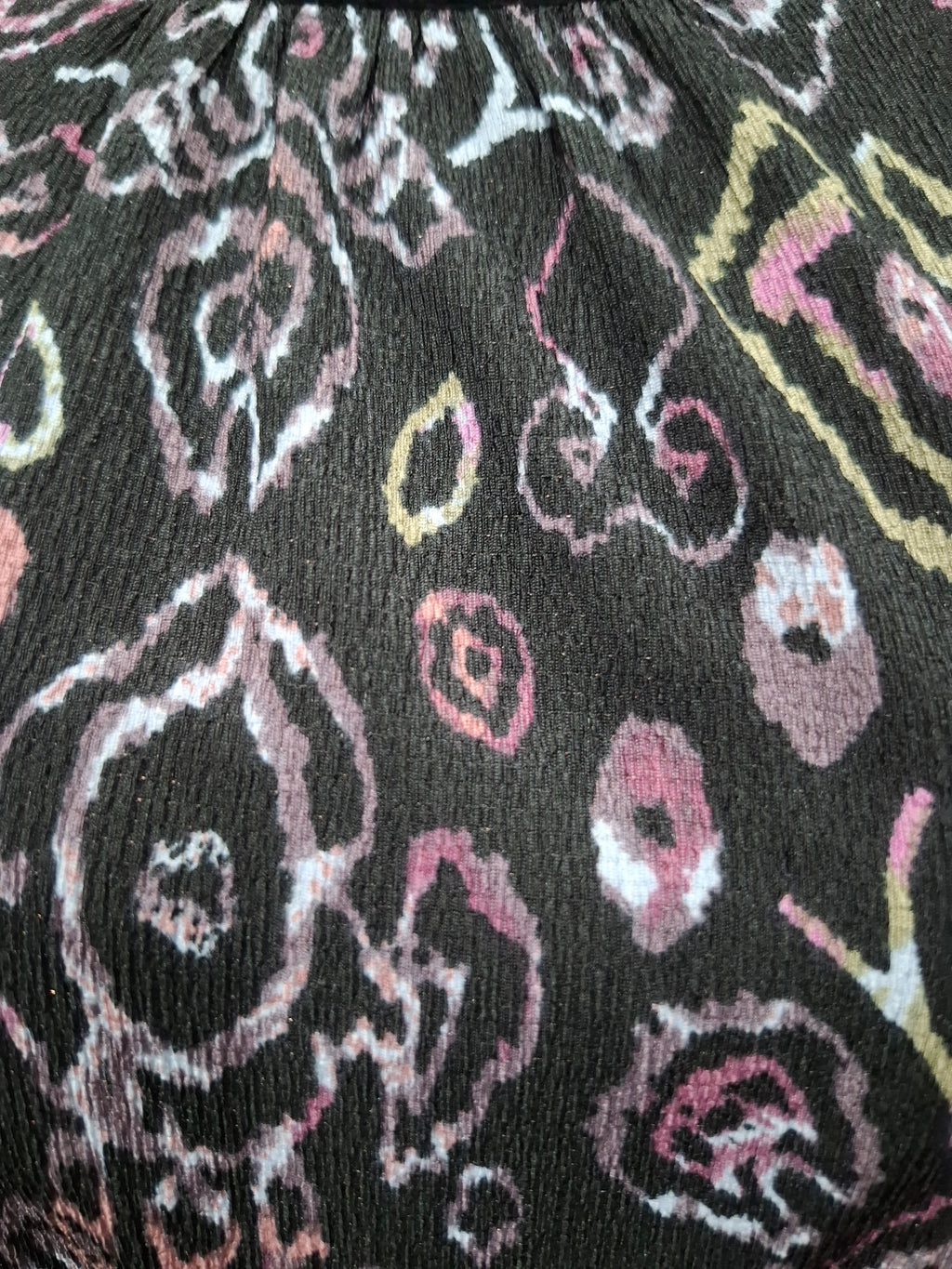 A close-up of a black fabric with a distressed, ikat-style floral pattern in pink, white, and yellow.