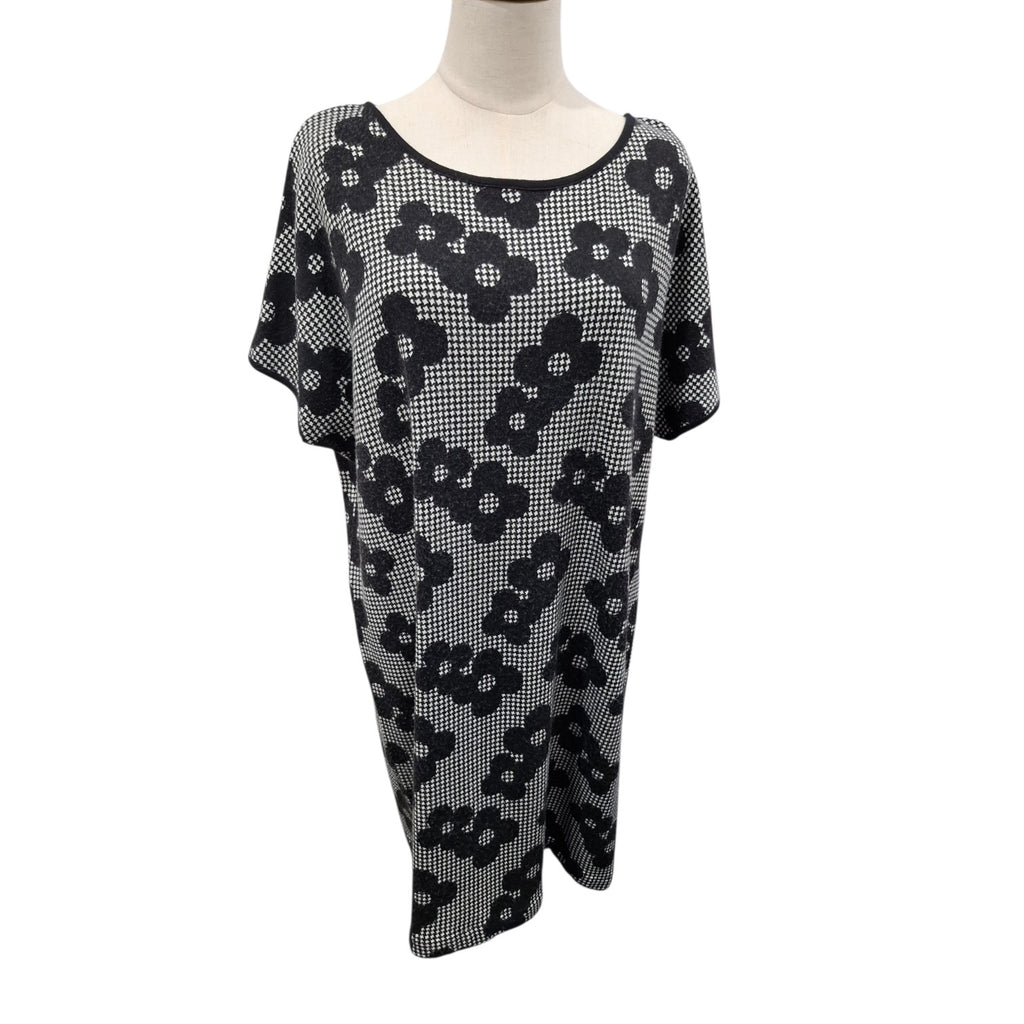 A black and white patterned knit tunic top with a scoop neckline and short sleeves, displayed on a mannequin torso against a white background.