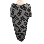 A short-sleeve knit dress with a black and white micro-check pattern and large black floral motifs, displayed on a mannequin torso against a white background.