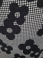 Close-up of a black and white woven fabric pattern featuring large floral motifs over a fine houndstooth background.