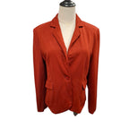 A rust-orange single-breasted blazer with notch lapels and flap pockets, displayed on a cream-colored dress form mannequin against a white background.