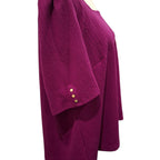A close-up side view of a magenta ribbed knit top on a mannequin, featuring three gold buttons on the sleeve cuff.