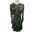 A long-sleeve wrap-style dress with a green botanical leaf pattern on a black background, displayed on a mannequin torso against a plain white background.