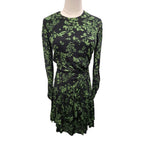 A long-sleeve wrap-style dress with a green botanical leaf pattern on a black background, displayed on a mannequin torso against a plain white background.