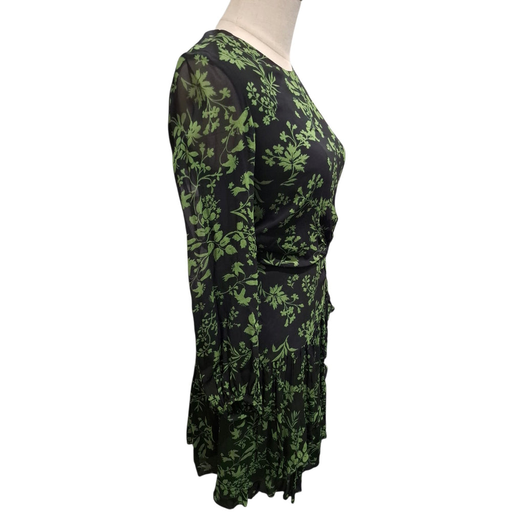 A black long-sleeve wrap dress with an all-over green floral pattern, displayed on a mannequin torso against a plain white background.