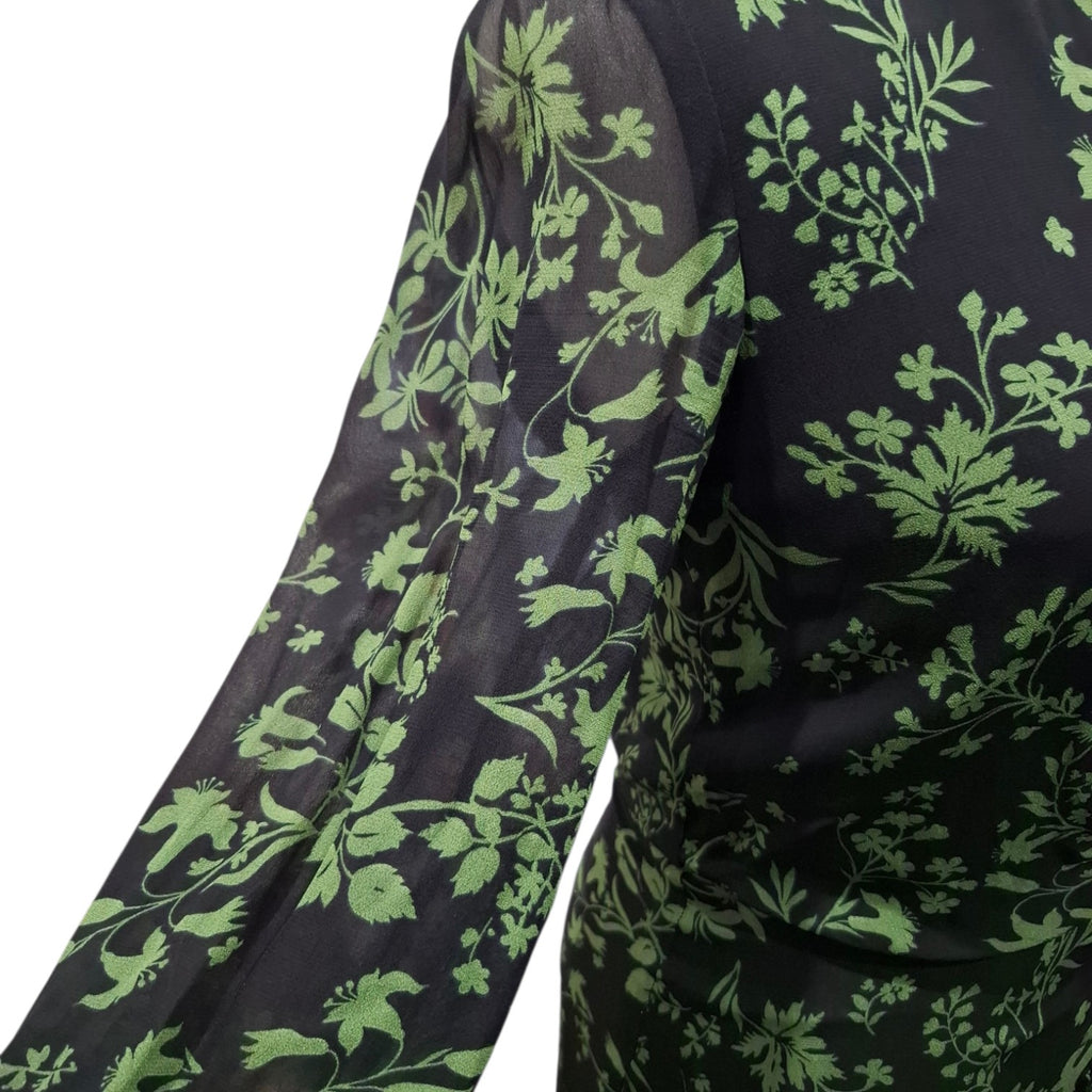 Close-up of a sheer black long-sleeve garment with a light green floral and bird pattern, shown against a white background.