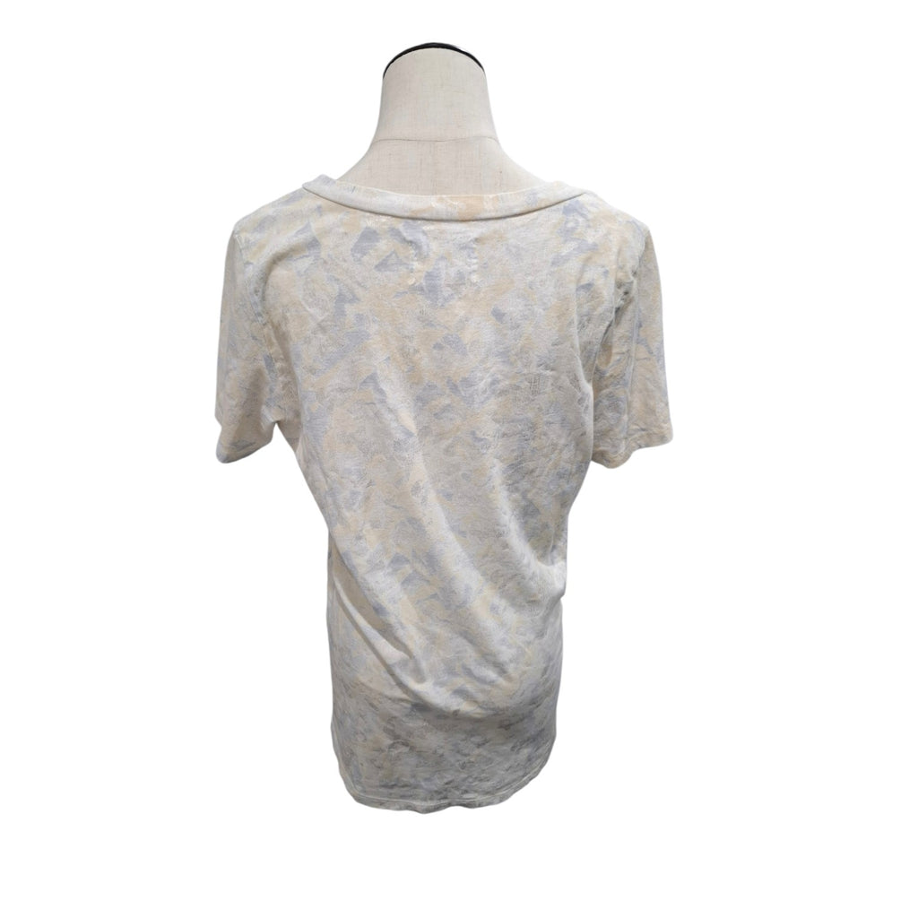 A short-sleeve t-shirt with a distressed, faded abstract pattern in beige, gray, and off-white, displayed on a mannequin torso against a plain white background.