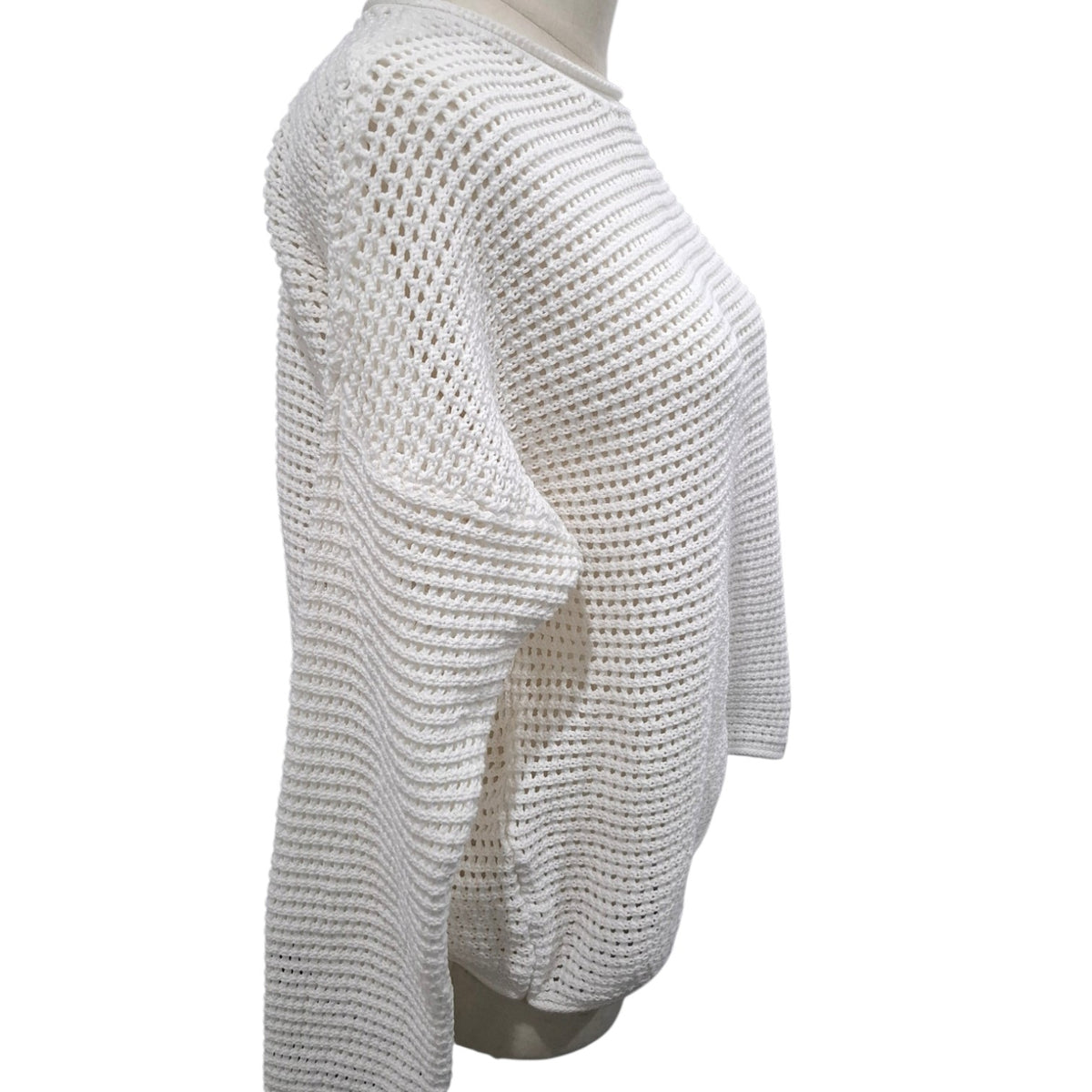 A white open-knit cropped sweater displayed on a mannequin torso against a plain white background.