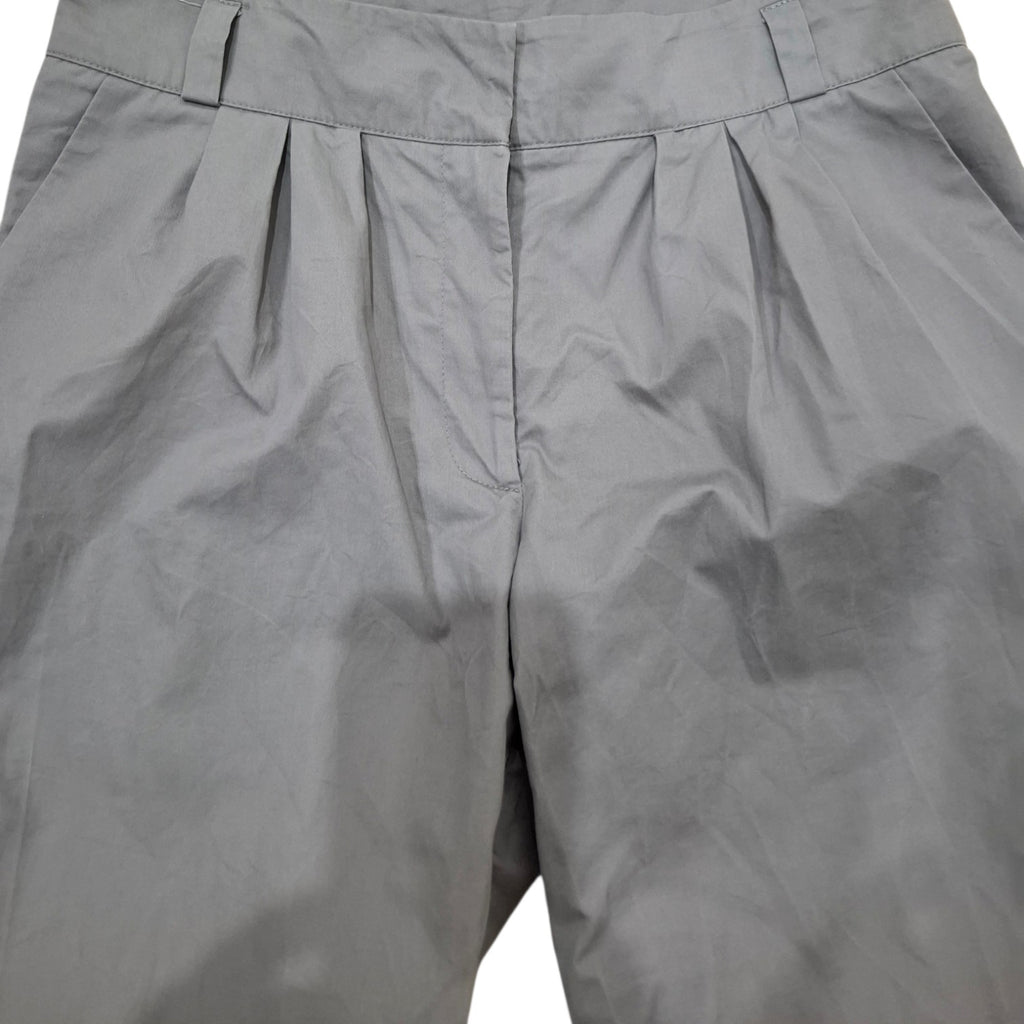 Close-up of gray pleated trousers showing the waistband, front center seam, and fabric texture.