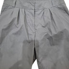 Close-up of gray pleated trousers showing the waistband, front center seam, and fabric texture.