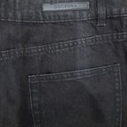 Close-up of the back waistband and pocket of dark gray denim jeans, showing a rectangular brand patch that reads DECIUBA.