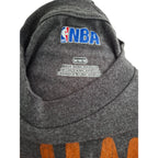 Close-up of the inside neck of a dark gray heathered sweatshirt featuring a blue and red embroidered NBA logo on the inner collar, with size text 'M/M/N' and 'MADE IN NICARAGUA' printed below it.