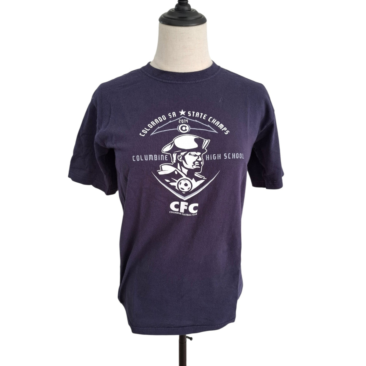 A navy blue short-sleeve t-shirt displayed on a mannequin torso against a white background. The shirt features a white graphic print on the front with the text 'COLUMBINE 2025 HIGH SCHOOL' and 'CFC' surrounding a mascot illustration.