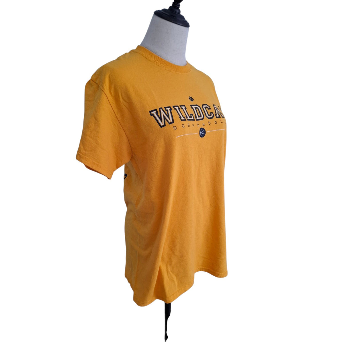 A yellow short-sleeve t-shirt displayed on a headless gray mannequin torso against a plain white background. The shirt features 'WILDCATS' printed across the chest in navy blue with a white outline, and a small circular logo underneath.