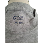 Close-up of a gray heather crewneck t-shirt on a mannequin, showing the inner neck label with the navy blue 'PORT and COMPANY' logo and 'ADULT M/M' text.