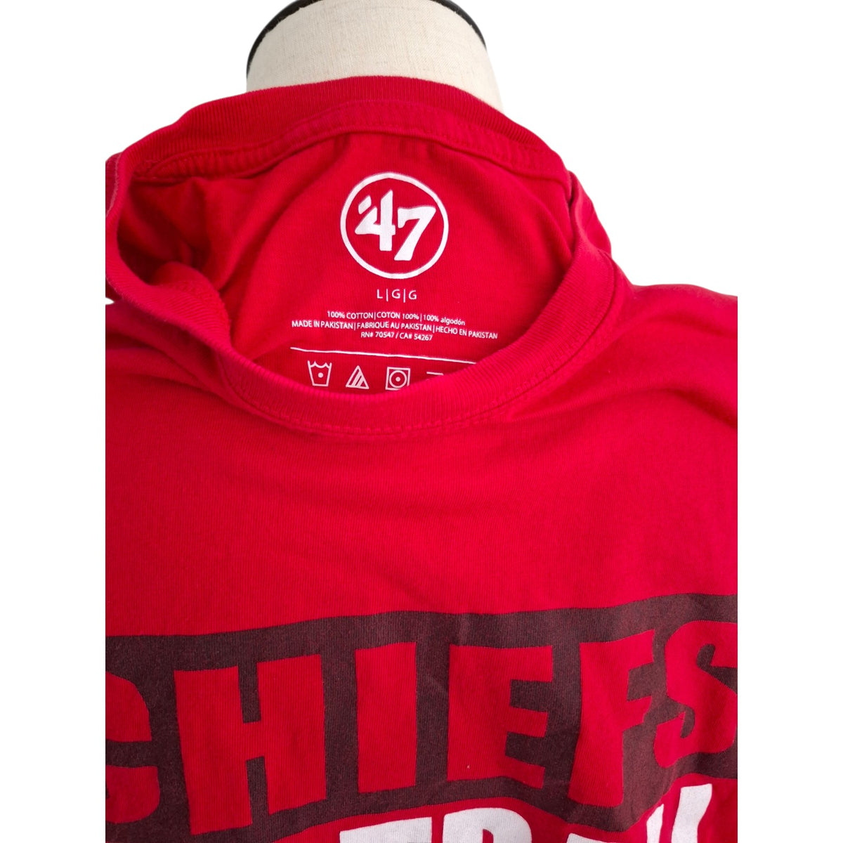 A close-up of a red 47 brand t-shirt on a mannequin, showing the inner neck label and part of the front graphic that reads 'CHIEFS'.