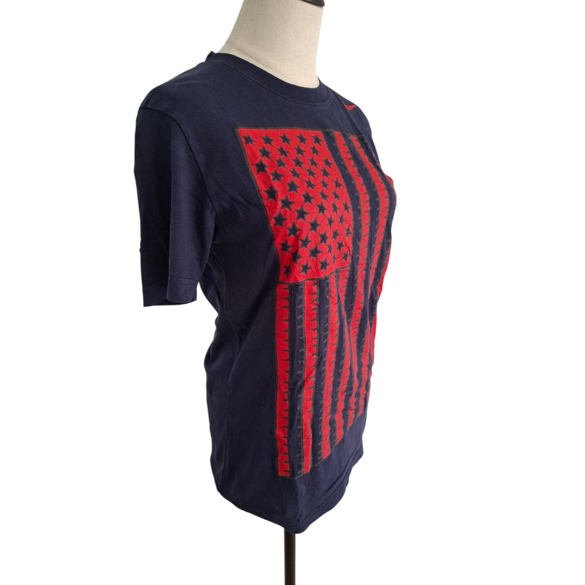 A navy blue short-sleeve t-shirt displayed on a mannequin torso, featuring a large red American flag graphic on the front with black stars and stripes.