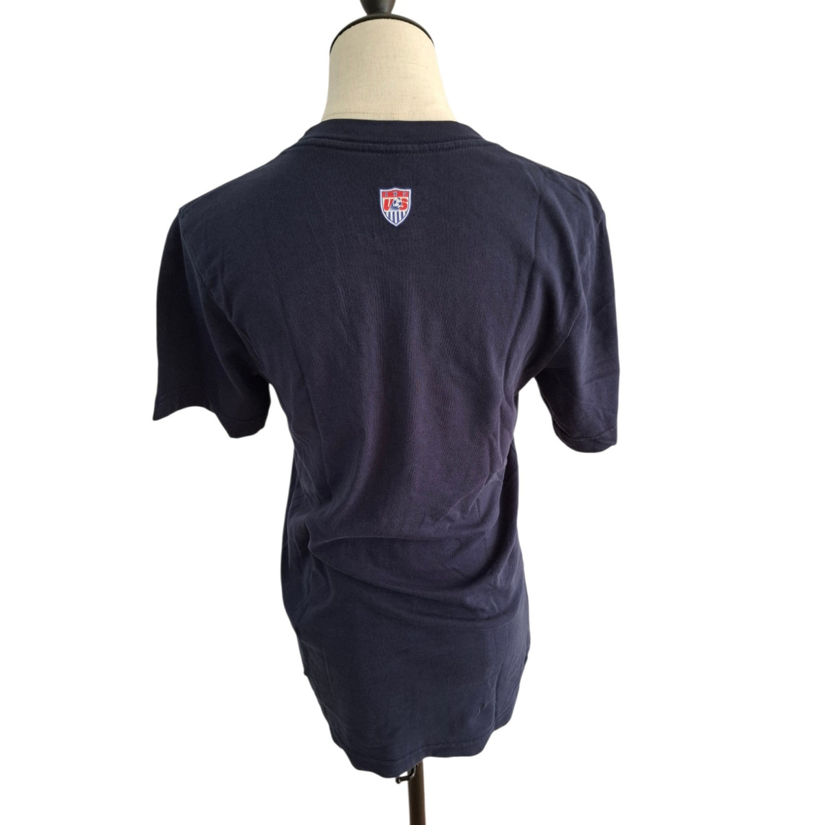 A dark navy blue short-sleeve t-shirt displayed on a mannequin torso, showing the back view with a small shield logo near the upper neck.