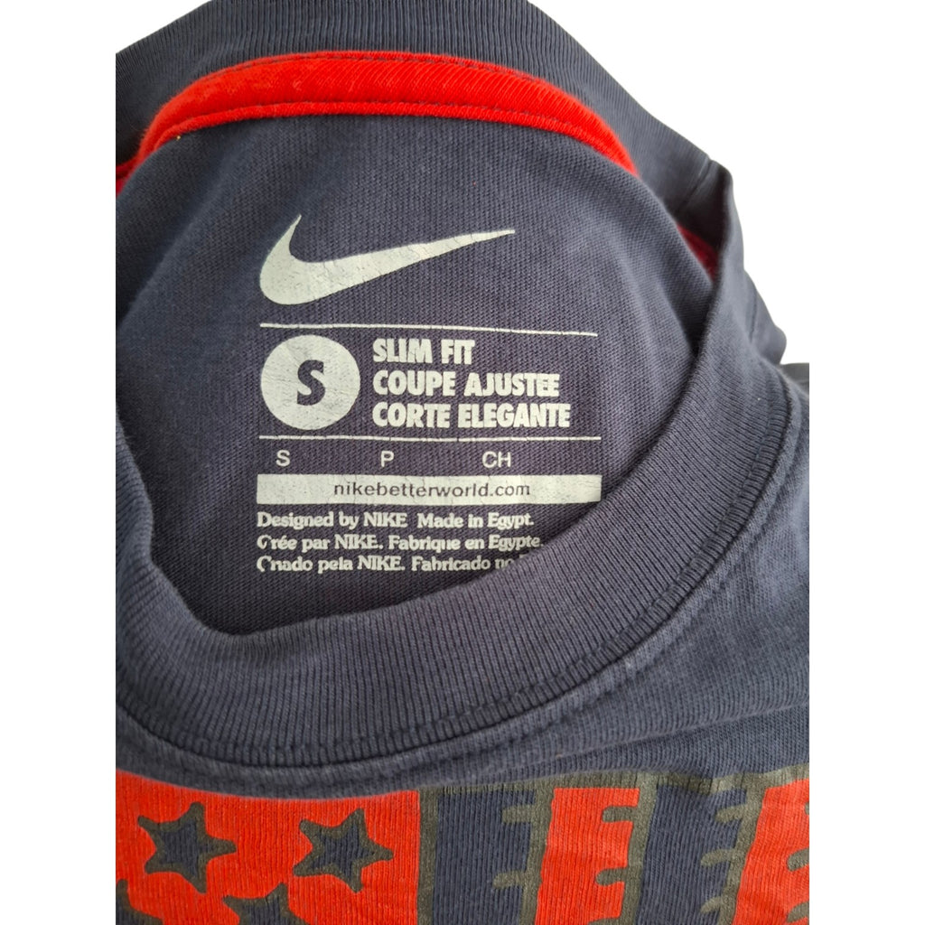 Close-up of the inside collar of a Nike Slim Fit t-shirt, showing the white Nike swoosh and size label on dark gray fabric with red trim.