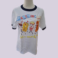 A white ringer t-shirt with dark navy blue collar and sleeve trim, featuring a colorful cartoon graphic of snack characters and the text 'LET'S ALL GO TO THE LOBBY' and 'Let's snack!'.