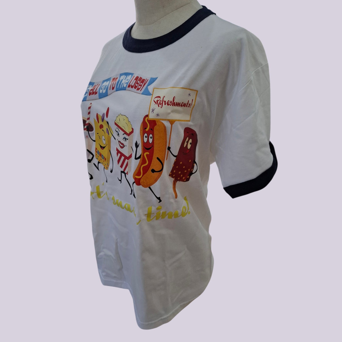 A white ringer t-shirt with black trim on the collar and cuffs, featuring a colorful cartoon graphic of hot dogs and candy canes with the words 'Hot Dogs to the Moon!' and 'Safreshments!' on a light gray background.
