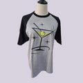 A gray and black raglan t-shirt displayed on a mannequin torso, featuring a graphic of a martini glass with an olive on a starry background.