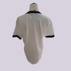 A short-sleeve ringer t-shirt shown from the back on a mannequin torso. The shirt is off-white with a dark navy blue collar and sleeve cuffs.