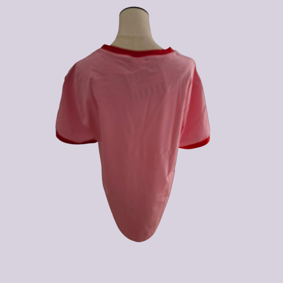 A pink short-sleeve t-shirt with red trim on the collar and sleeve cuffs, displayed on a beige mannequin torso against a light gray background.