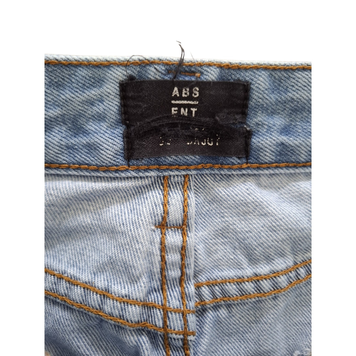 Close-up of the waistband of light-wash blue denim jeans, showing a black brand label that reads 'ABS ENT' and 'SEMPER JUNG'.