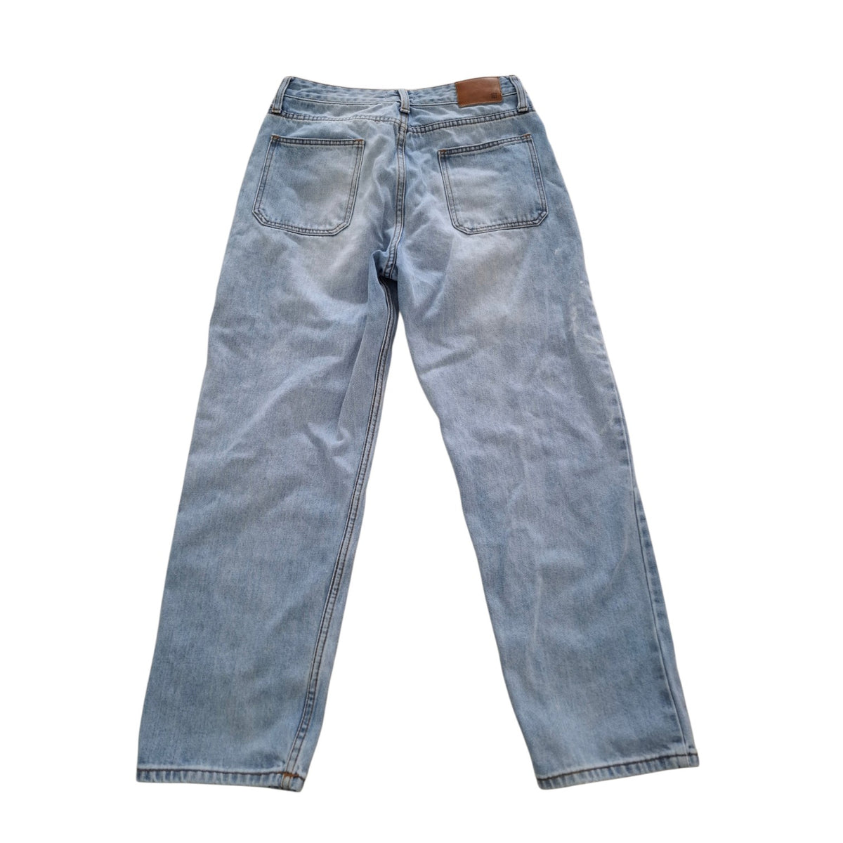Light wash blue denim jeans shown from the back, featuring a classic five-pocket design and a brown leather patch at the back waistband, laid flat on a white background.