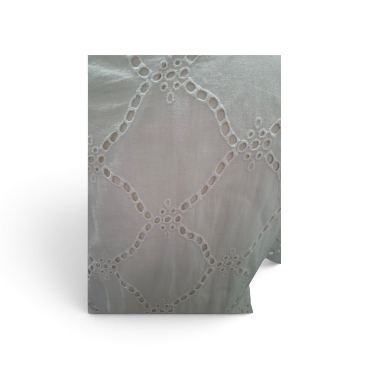 A close-up of a light gray eyelet lace fabric with a repeating geometric floral pattern, shown standing against a white background.