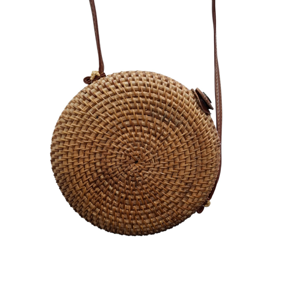 A round woven straw crossbody bag with a brown leather strap, shown against a plain white background.