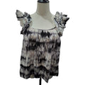 A women's sleeveless top with ruffled shoulder straps, displayed on a cream-colored dress form mannequin. The top features a black, gray, and beige tie-dye pattern.