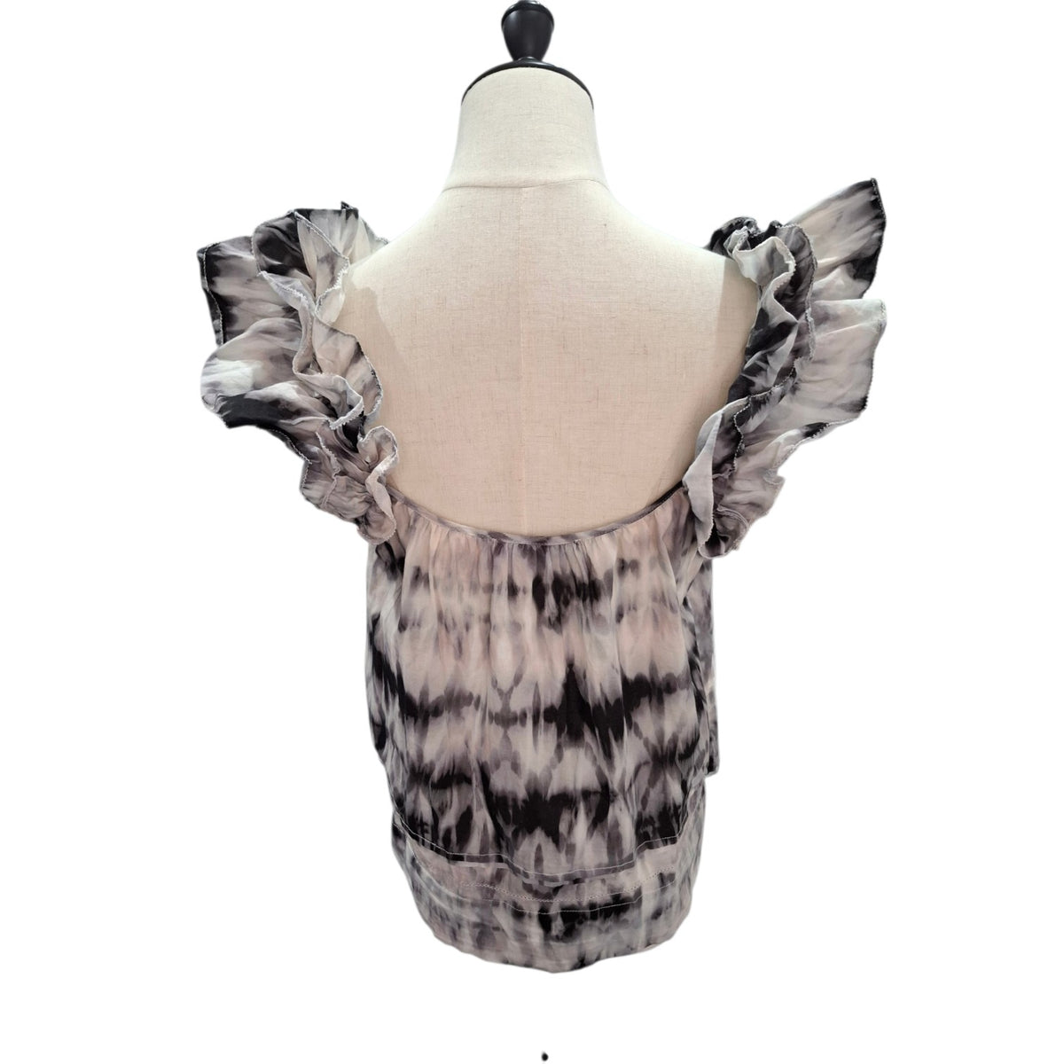 A women's top displayed on a dress form mannequin, showing the back view. The top features a black and white tie-dye pattern with dramatic ruffled shoulder straps and a scoop neckline.