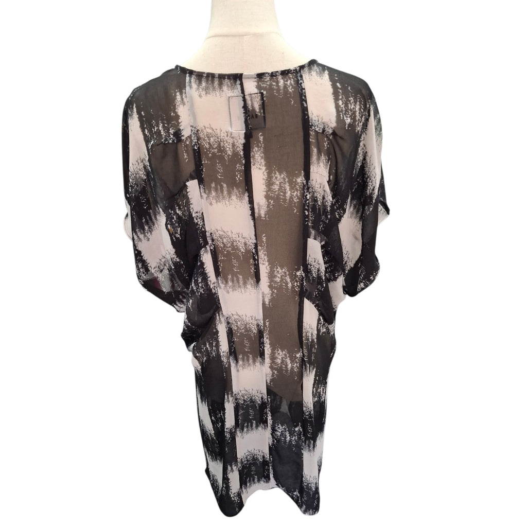 A sheer black and beige abstract patterned blouse displayed on a mannequin torso against a white background.